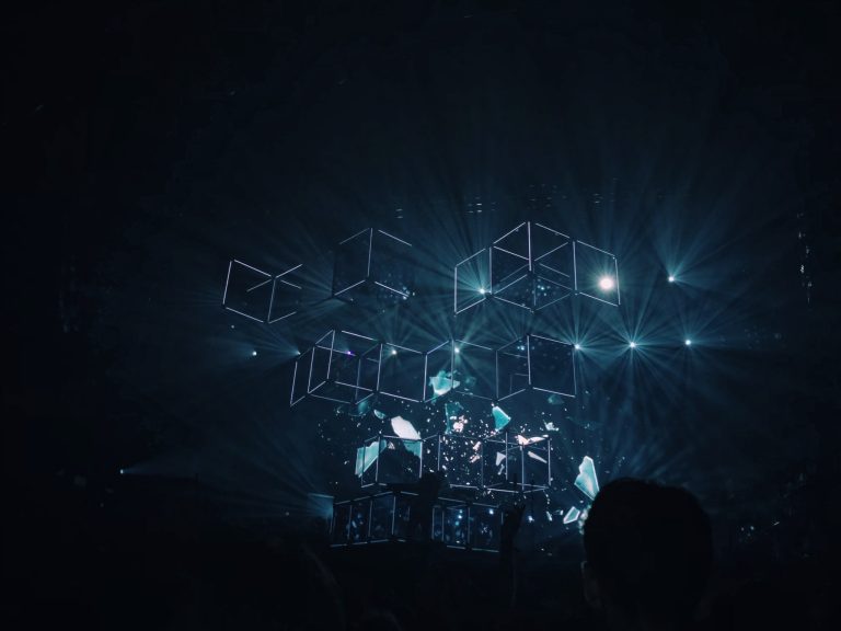 A group of people standing in front of a stage with lights.